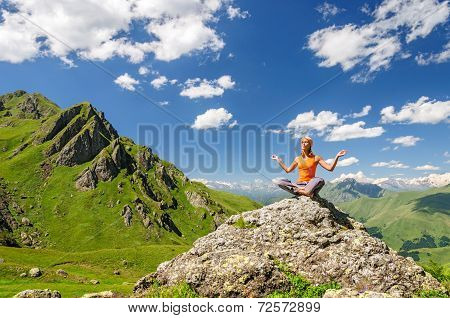 Young woman sitting in yoga pose in mountains