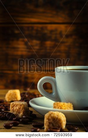 Cup of coffee in the old rustic style with cane sugar cubes and coffee beans.