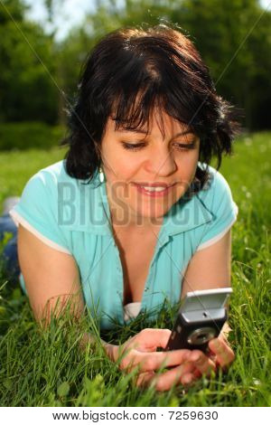 Mulher deitada no gramado usando Mobile