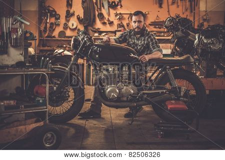Mechanic building vintage style cafe-racer motorcycle  in custom garage