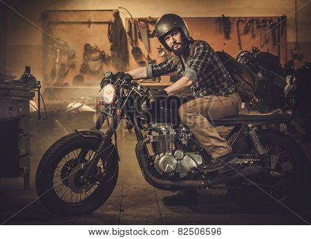 Rider and his vintage style cafe-racer motorcycle in customs garage 