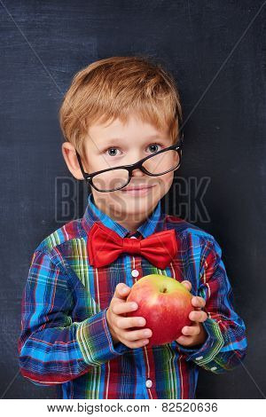 Mixed-up ginger primary school age boy holding red apple