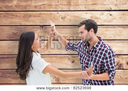 Fearful brunette being overpowered by boyfriend against wooden planks background