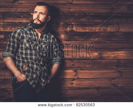 Handsome man wearing checkered  shirt in wooden rural house interior 
