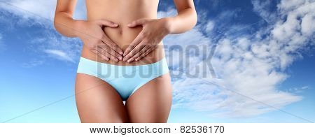 hands shape heart on the belly of woman