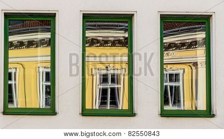 a renovated house reflected in modern windows of an office building