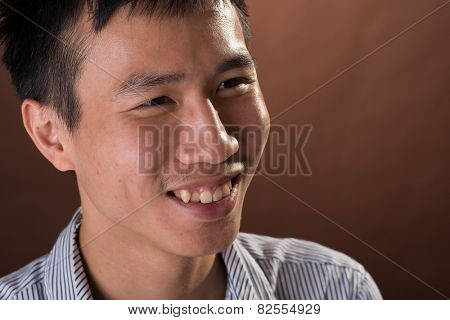 Young Chinese frank businessman smiling, closeup portrait in studio.