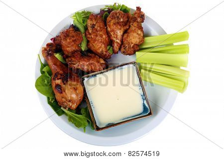Buffalo Chicken Wings with Celery and Blue Cheese Dressing and Lettuce on a White Plate isolated on white with room for your text. Buffalo Wings are enjoyed by millions of people around the world.