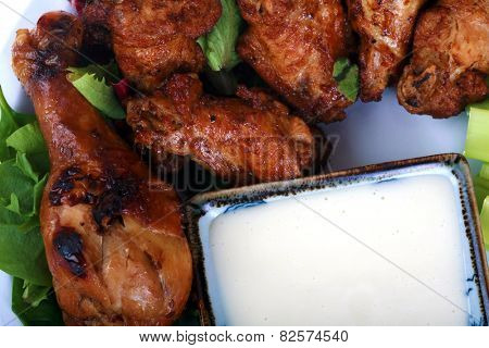 Buffalo Chicken Wings with Celery and Blue Cheese Dressing and Lettuce on a White Plate isolated on white with room for your text. Buffalo Wings are enjoyed by millions of people around the world.