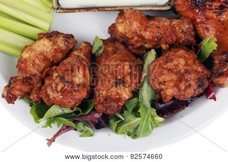 Buffalo Chicken Wings with Celery and Blue Cheese Dressing and Lettuce on a White Plate isolated on white with room for your text. Buffalo Wings are enjoyed by millions of people around the world.