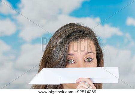 brunette holding a paperplane in front of cloud themed background