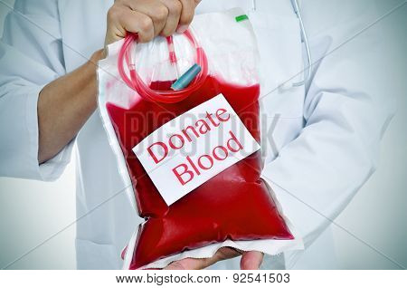 closeup of a doctor holding a blood bag with a sticker with the text donate blood