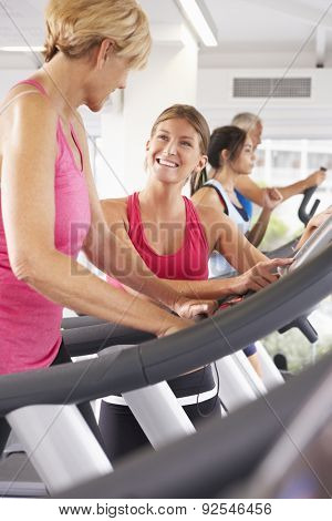 Woman On Running Machine In Gym Encouraged By Personal Trainer