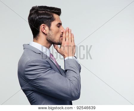 Side view portrait ofa  businessman praying over gray background