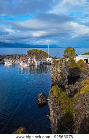 White fishing boat in the harbor pier fishing village Arnastapi. Sunset on the sea fjord in Iceland
