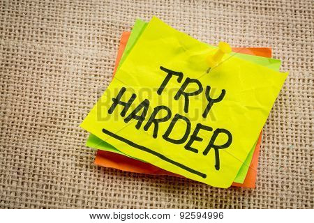 try harder - motivation words on a  yellow sticky note against burlap canvas
