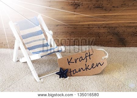 Sunny Summer Label With Sand And Aged Wooden Background. German Text Kraft Tanken Means Relax. Deck Chair For Holiday Or Vacation Feeling.