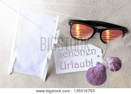 Sunny Summer Label With German Text Schoenen Urlaub Means Happy Holidays. Flat Lay View. Summer Decoration With Deck Chair, Seashells And Sunglasses. Greeting Crad With Sand Background