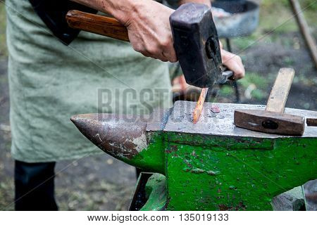 blacksmith forges detail. Blacksmith working outdoors. Master works on the anvil.