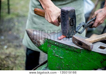 blacksmith forges detail. Blacksmith working outdoors. Master works on the anvil.