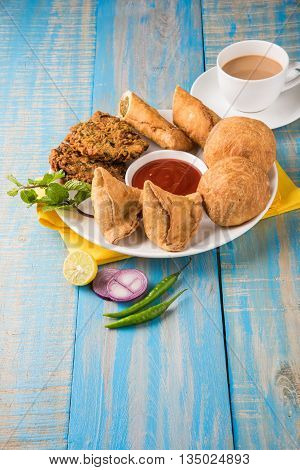 coriander vada or kothimbir vada, samosa, kachori, daal vada on brown wooden planks. indian assorted snacks. Indian snacks combination. Indian snacks group, indian favourite snacks, asian spicy snacks
