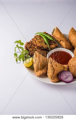 coriander vada or kothimbir vada, samosa, kachori, daal vada on brown wooden planks. indian assorted snacks. Indian snacks combination. Indian snacks group, indian favourite snacks, asian spicy snacks