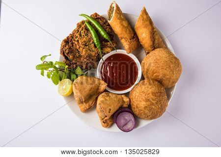 coriander vada or kothimbir vada, samosa, kachori, daal vada on brown wooden planks. indian assorted snacks. Indian snacks combination. Indian snacks group, indian favourite snacks, asian spicy snacks