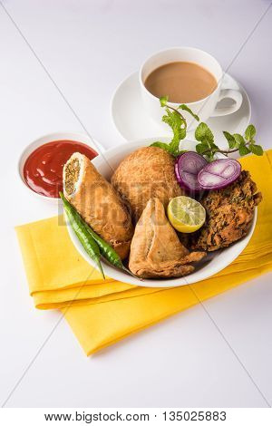coriander vada or kothimbir vada, samosa, kachori, daal vada on brown wooden planks. indian assorted snacks. Indian snacks combination. Indian snacks group, indian favourite snacks, asian spicy snacks