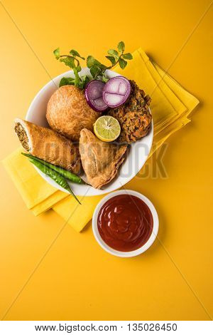 coriander vada or kothimbir vada, samosa, kachori, daal vada on brown wooden planks. indian assorted snacks. Indian snacks combination. Indian snacks group, indian favourite snacks, asian spicy snacks