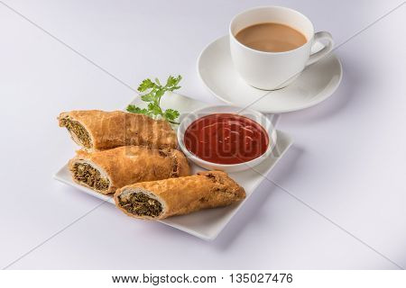 spring rolls or kothimbir vadi or sambar vadi or coriander spring rolls, indian snacks, tastes great with tea and tomato ketchup or tomato sauce, in square white plate over colourful background