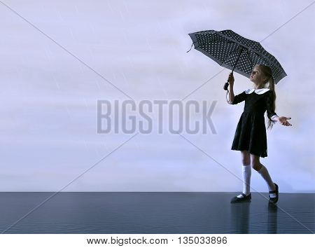 cute little girl with an umbrella walking on wet asphalt. background for inscriptions