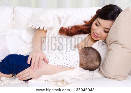 Beautiful asian woman breastfeeding her six months old baby boy