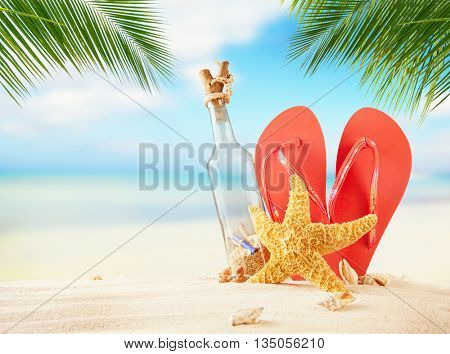 Empty glass and flipflops on beach, blur sea on background. Summer exotic relaxation concept. Copyspace for text