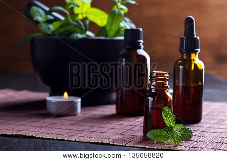 Closeup of mint essential oils and candle, aromatherapy setting.Selective focus