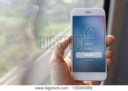 Hand holding smartphone with member loging screen on train window background