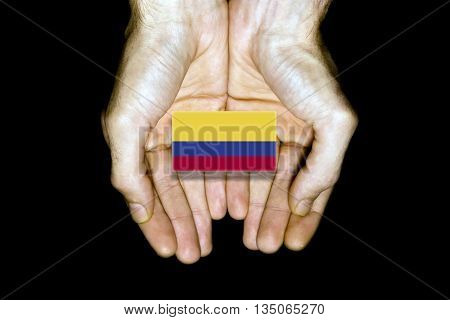 Flag of Colombia in hands isolated on black background.