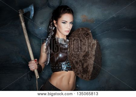 Medieval woman amazon holding a shield and an ax.