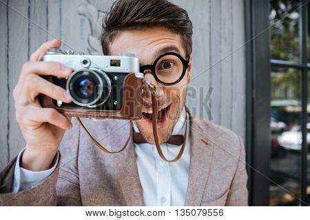 Happy funny stylish nerd holding camera outdoors