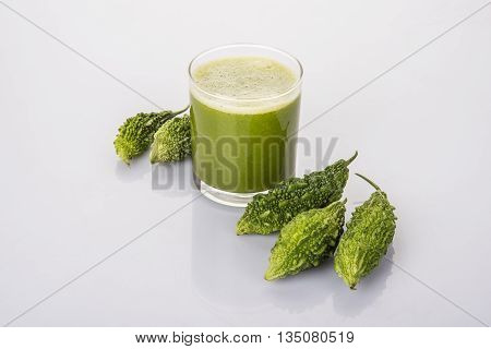 Herbal juice of green momodica in a glass with sliced vegetables, karela juice or bitter gourd juice