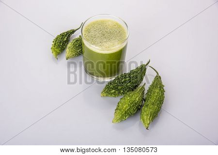 Herbal juice of green momodica in a glass with sliced vegetables, karela juice or bitter gourd juice