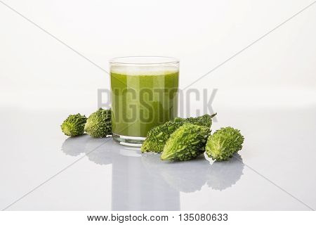 Herbal juice of green momodica in a glass with sliced vegetables, karela juice or bitter gourd juice
