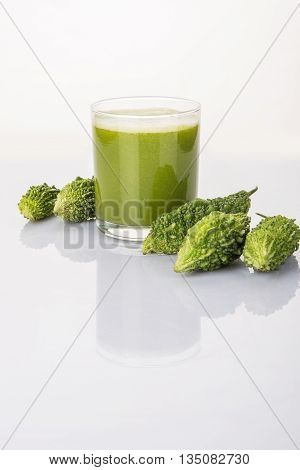 Herbal juice of green momodica in a glass with sliced vegetables, karela juice or bitter gourd juice