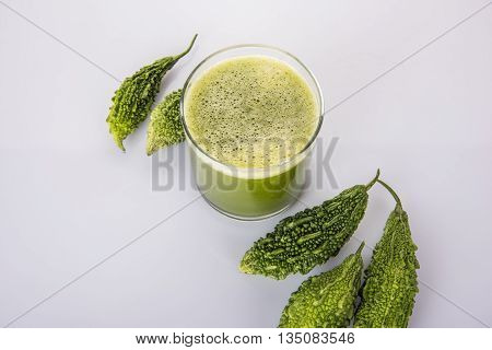 Herbal juice of green momodica in a glass with sliced vegetables, karela juice or bitter gourd juice