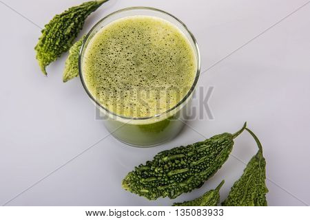 Herbal juice of green momodica in a glass with sliced vegetables, karela juice or bitter gourd juice