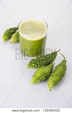 Herbal juice of green momodica in a glass with sliced vegetables, karela juice or bitter gourd juice