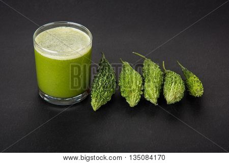 Herbal juice of green momodica in a glass with sliced vegetables, karela juice or bitter gourd juice
