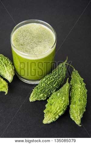 Herbal juice of green momodica in a glass with sliced vegetables, karela juice or bitter gourd juice