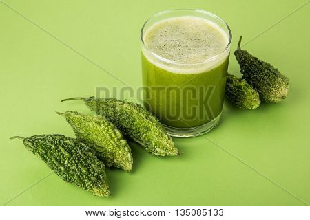 Herbal juice of green momodica in a glass with sliced vegetables, karela juice or bitter gourd juice