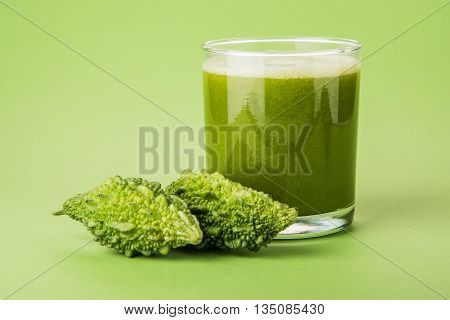 Herbal juice of green momodica in a glass with sliced vegetables, karela juice or bitter gourd juice