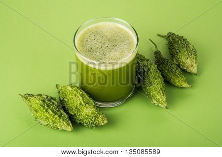 Herbal juice of green momodica in a glass with sliced vegetables, karela juice or bitter gourd juice